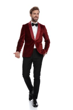 Mutlu damat kırmızı kadife smokin giyiyor ve gülümsüyor.