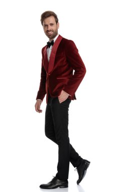 Kırmızı kadife smokin giyen mutlu genç moda adamı.