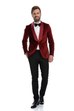 Gülümseyen genç damat kırmızı kadife smokin giyiyor. 