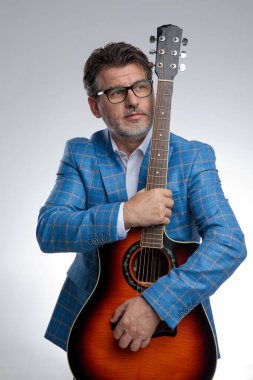 İş adamı ayakta duruyor ve gitarı sıkıca tutuyor.