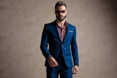 İşadamı ayakta duruyor ve güçlü bir tavırla kameraya bakıyor.