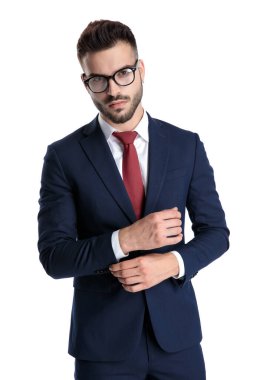 Kendine güvenen bir adam güneş gözlüğü takarken kolunu düzeltiyor.