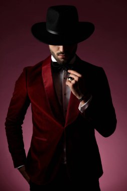 Gizemli moda adamı kırmızı kadife smokin giyiyor ve yayı tamir ediyor.