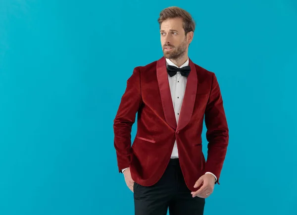 Elegant ung man bär röd sammet smoking och tittar åt sidan — Stockfoto