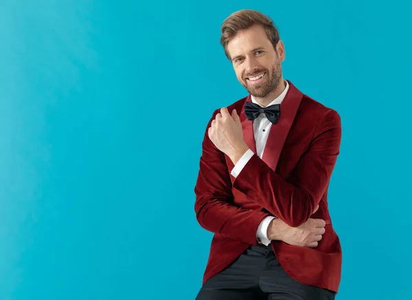 Homme élégant et souriant portant smoking en velours rouge sur fond bleu — Photo