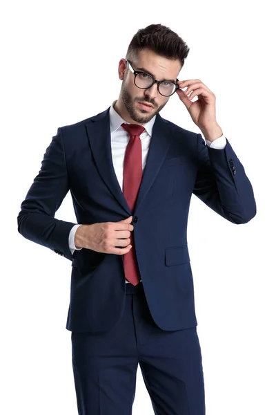 Joven hombre de negocios inteligente ajustando sus gafas y chaqueta —  Fotos de Stock