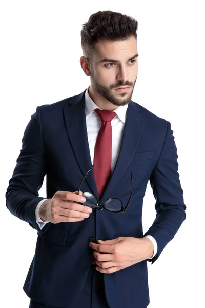 Przystojny młody biznesmen trzyma okulary i dostosowuje swoje — Zdjęcie stockowe