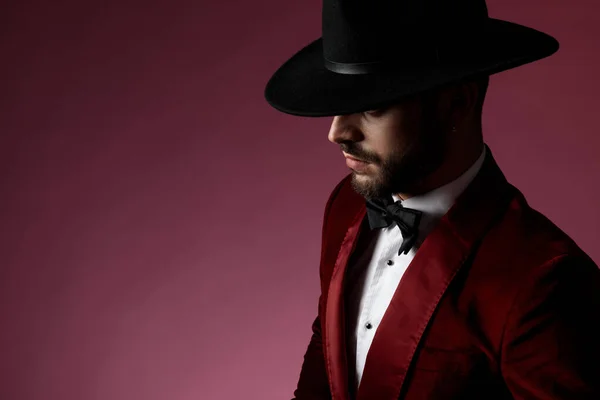 Таинственный молодой человек в красном бархатном смокинге и черной шляпе — стоковое фото
