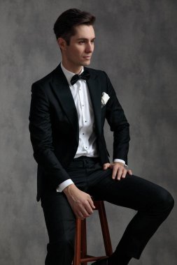 şık bir damat smokin giyer ve yanını kollar.