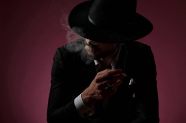 Düşünceli bir adam gözlerini kaçırıp sigara içiyor. 