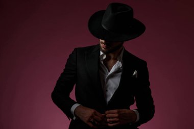 Yakışıklı adam gömleğinin düğmelerini açıyor ve başka tarafa bakıyor.