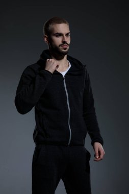 Genç manken spor takımı giyiyor ve ceketini tamir ediyor.