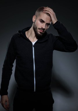 Gri arka planda spor takımı giyen çekici bir genç.