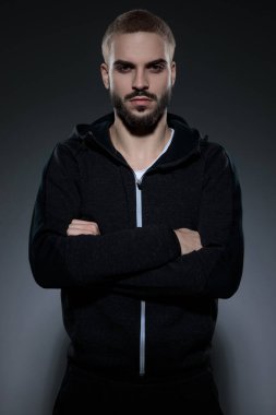 Genç manken spor takımı giyiyor ve kollarını kavuşturuyor.