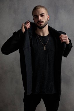 Siyah uzun paltosunu ayarlayan sert bir genç adam. 