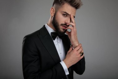 Düşünceli damat parmaklarını alnında tutuyor.