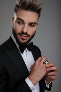 Hiç etkilenmemiş damat yüzüğünü ayarlıyor ve kendi yüzüğüne bakıyor.