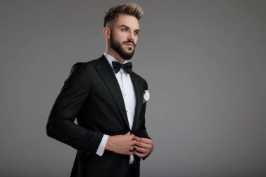 Serious looking groom unbuttoning his jacket and looking away clipart