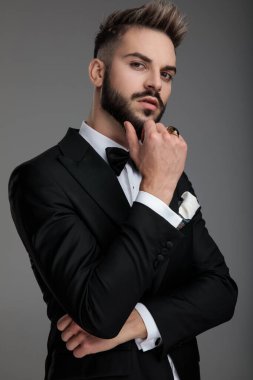 Yakışıklı damat elini çenesinde tutuyor.