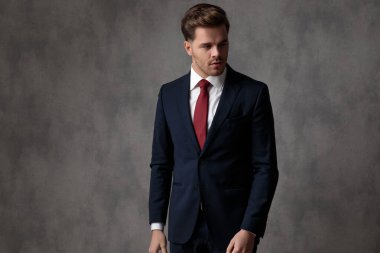 Endişeli işadamı mavi bir takım elbise giyerken başka tarafa bakıyor.