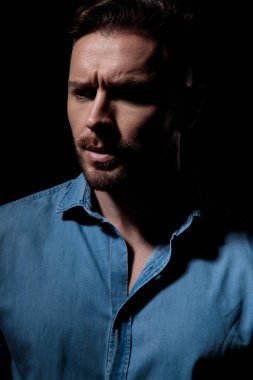 Sıradan bir adam gölgelerde dikilip başka tarafa bakıyor.