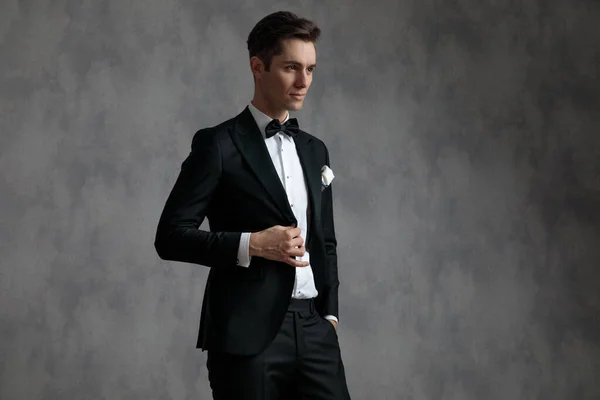 Jovem elegante noivo vestindo smoking e arranjando casaco — Fotografia de Stock