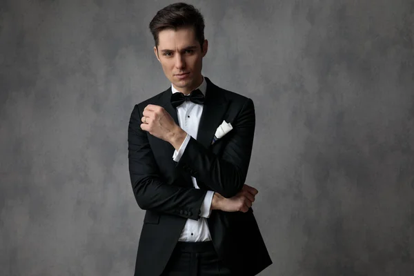 Elegante hombre de moda con esmoquin negro sobre fondo gris — Foto de Stock