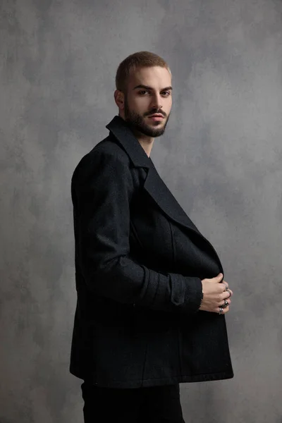 Hombre serio mirando fijando su abrigo largo negro — Foto de Stock
