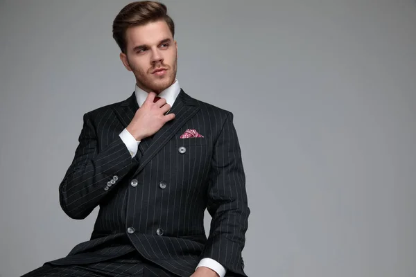 Jovem homem de moda olhando para o lado e fixação de gravata — Fotografia de Stock