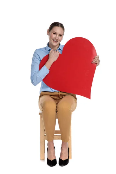 Щаслива молода бізнес-леді тримає велике червоне серце — стокове фото
