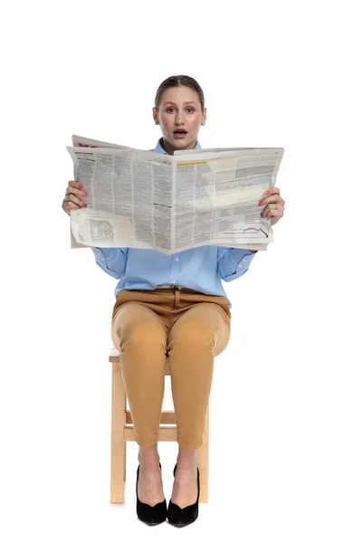 Mujer sorprendida leyendo periódico sobre fondo blanco — Foto de Stock