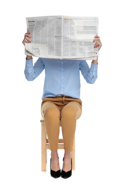 Junge Geschäftsfrau versteckt Gesicht hinter Zeitung — Stockfoto