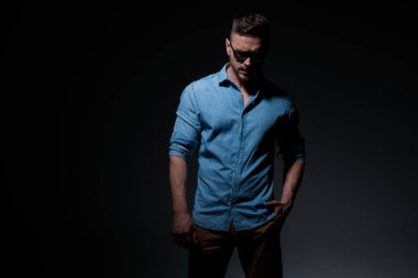 Sıradan bir adam, el ele durur ve aşağıya bakar. 