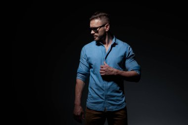 Sıradan bir adam gömleğini düzeltiyor ve dramatik bir bakışla aşağı bakıyor.