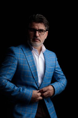 İş adamı duruyor ve ceketin düğmesine el ele tutuşuyor.