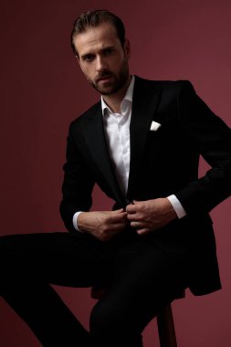 Yakışıklı, zarif adam ileriye bakıyor ve ceketinin düğmelerini açıyor. 