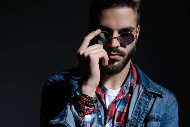 Tough casual man taking off his sunglasses 