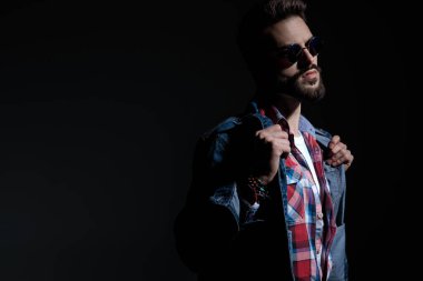 Motive olmuş genç adam ceketini ayarlıyor ve başka tarafa bakıyor.