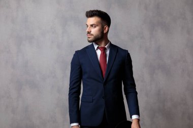 Düşünceli iş adamı başını çeviriyor ve şapkasını tutuyor.