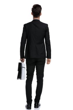 Elinde evrak çantası olan motive olmuş bir iş adamının arka görüntüsü.