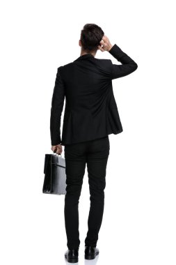 Elinde evrak çantası olan güvenilmez bir iş adamının arka görüntüsü.