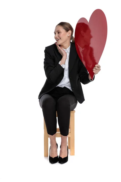 In love businesswoman holding red heart and looking aside — Stock Photo, Image