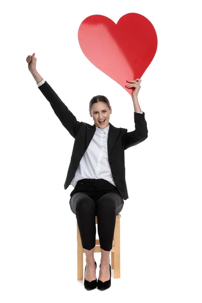 Business woman holding red heart and one fist up — стоковое фото