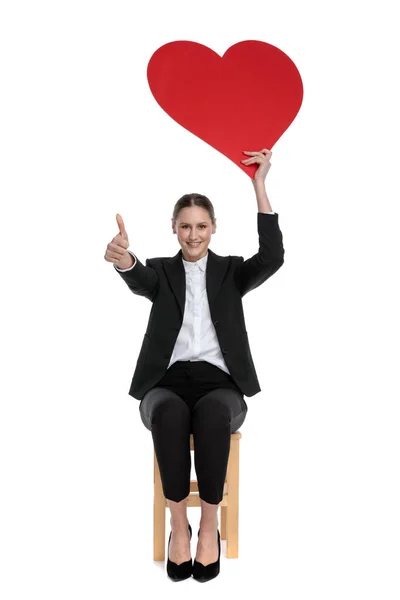 İşçi kadın kırmızı kalp tutuyor ve "Tamam" işareti yapıyor. — Stok fotoğraf