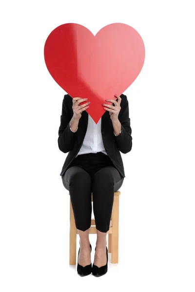 Podnikatelka sedí a skrývá se za velkým červeným srdcem — Stock fotografie