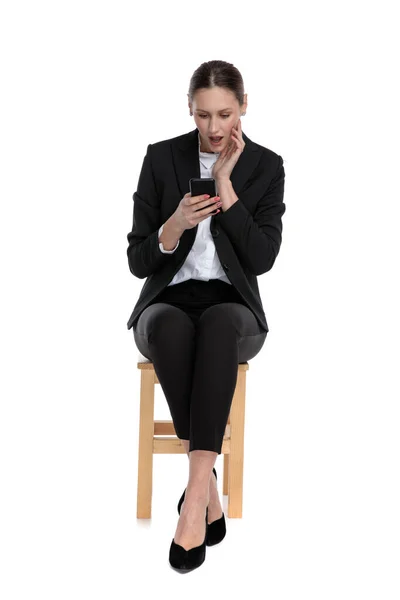 Businesswoman holding phone on hand and looking at screen shocke — Stock Photo, Image
