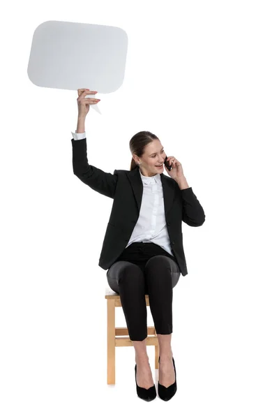 Mujer de negocios sosteniendo el habla burbuja y teléfono mirando a un lado —  Fotos de Stock