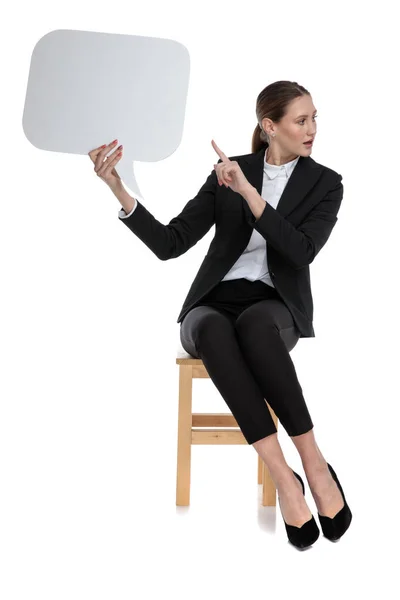 Geschäftsfrau sitzt und zeigt auf die Sprechblase — Stockfoto