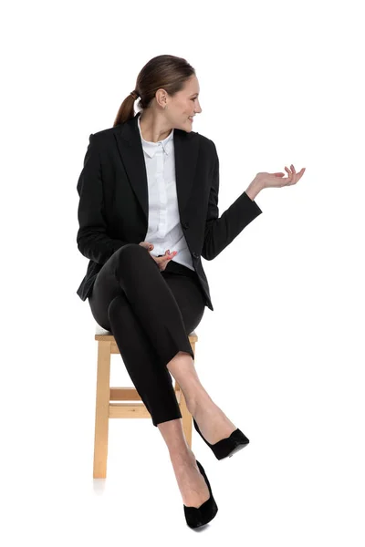 Donna d'affari seduta e che presenta a un lato — Foto Stock