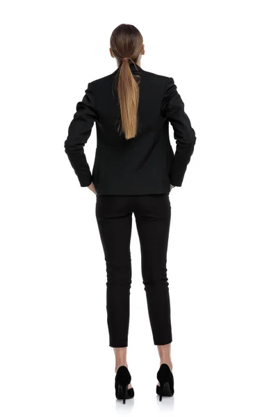 Affärskvinna stående med händerna i fickorna i bakvyn — Stockfoto